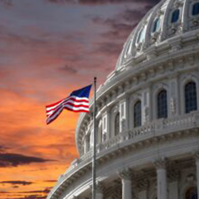 the american flag waiving infront of the capitol builind with an angry sky in the background